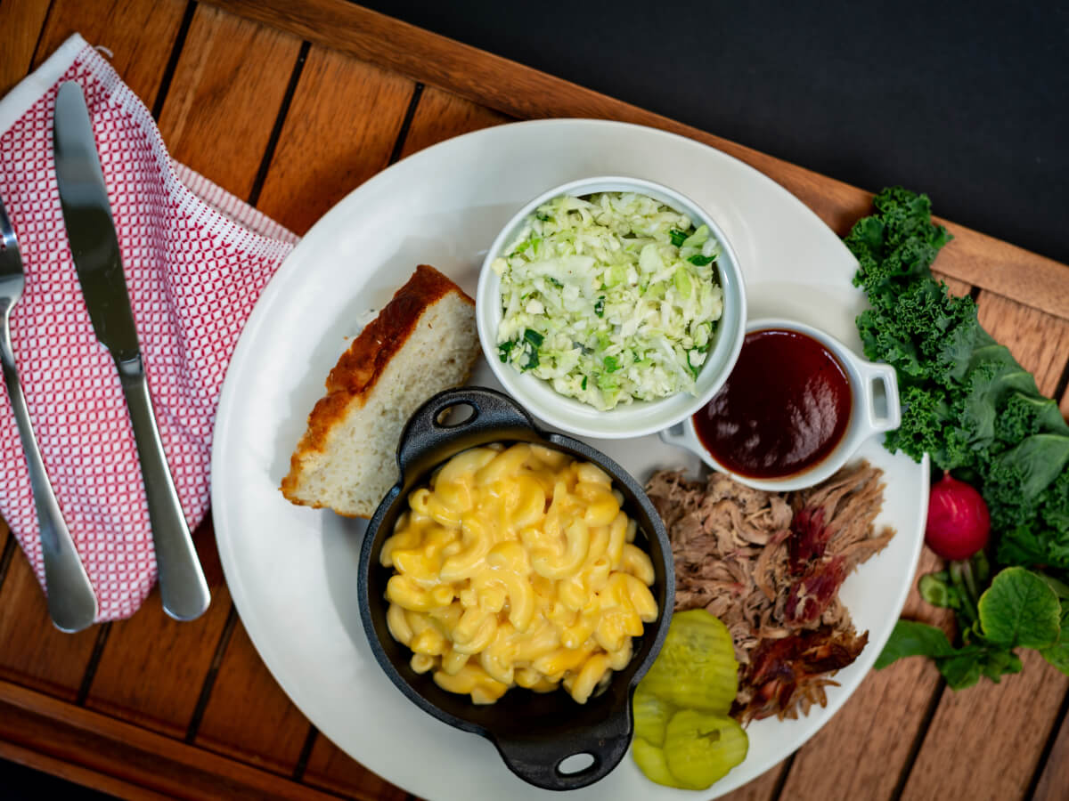 Whitt's pulled pork plate with macaroni and cheese, coleslaw, bread, pickles, and barbecue sauce